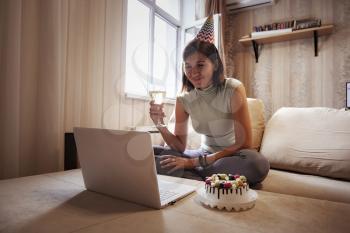 woman celebrating birthday online in quarantine time. Woman celebrating her birthday through video call virtual party with friends. Authentic decorated home workplace. Coronavirus outbreak 2020.