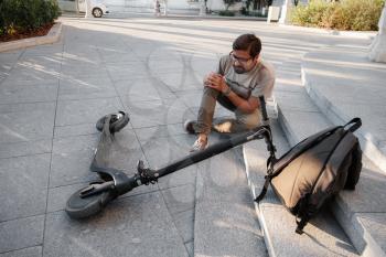 Young Man Accident With An Electric Scooter On Street. A man fell from a scooter on a city street.