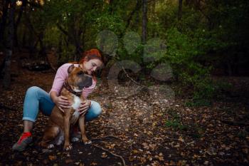 redhaired woman with her dog have fun on the walking. idea and concept of free time, happiness, care and freedom, long walks in the forest