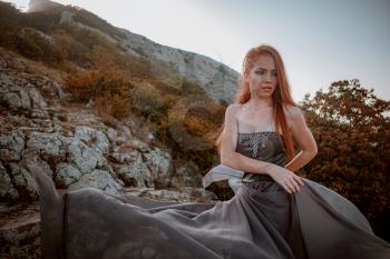 beautiful furious scandinavian warrior ginger woman in grey dress with metal chain mail. Woman is a Viking. Fantasy. Book Cover. beautifully flying dress