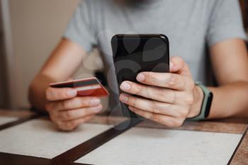 hipster young man shopping online with credit card using smart phone at home. Indoor. online shopping concept.