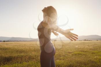 Young girl spreading hands with joy and inspiration facing the sun. She is enjoying serene nature workout vacation outdoors. asian beauty.