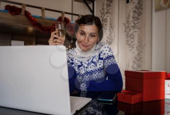 Happy asian woman wearing blue sweater holding glass of champagne, talking with family, social distance friend by video conference call meeting chat at home. stay home vocation, Christmas party online