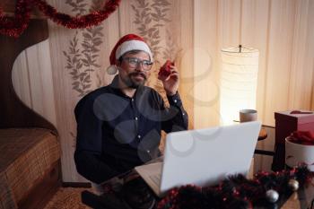 Virtual Christmas day house party. Man smiling wearing Santa hat Business video conferencing Online team meeting video conference calling from home.