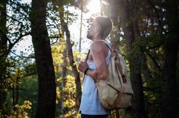 Man Traveler with backpack hiking outdoor in summer sunset forest. Travel Lifestyle and Adventure concept.