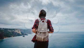 woman traveling with backpack tourist on seashore in summer. Enjoying Beautiful clouds sky among Mighty Cliffs Meeting Ocean. the idea and concept of freedom, vacation and discovery