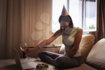 Lady celebrating birthday online in quarantine time. Woman celebrating her birthday through video call virtual party with friends. Authentic decorated home workplace. Coronavirus outbreak 2020.