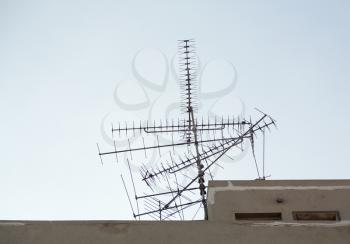 Confused set of TV aerials or antennae pointing in many directions on rooftop
