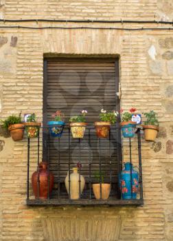 Flower decked balcony window in narrow streets in ancient city of Toledo, Spain, Europe