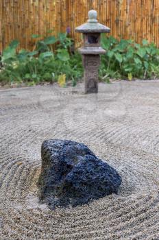 Large lava rock anchors the Japanese raked stone Zen garden with lantern and bamboo fence in Kauai, Hawaii