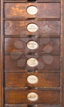 Wooden drawers of an ancient filing system with hand lettered labels for each subject