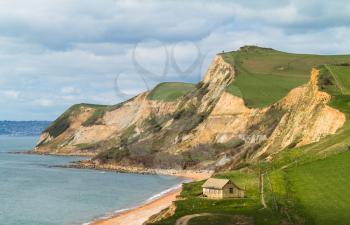 Small cottage on the beach by the side of the dramatic cliffs and headland at West Bay in Dorset used as the location for the Broadchurch TV series