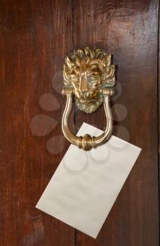 Envelope with space for text placed under a brass lion head door knocker on old oak door