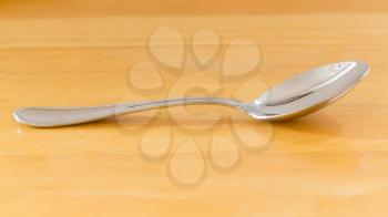 Decorated serving or dessert spoon in side view on wooden table or cutting board