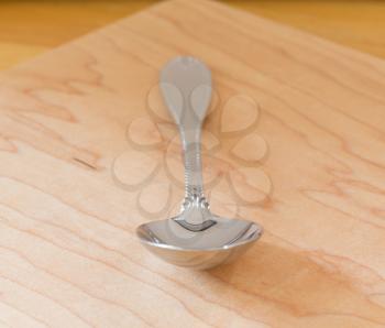 Decorated serving or dessert spoon in front view on wooden table or cutting board
