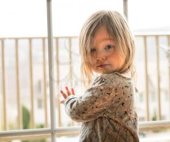 Young caucasian female toddler looking seriously at the camera with strong backlighting