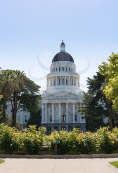 Backlit morning scene of the front of the California State Capitol building in the capital of Sacramento with roses framing the scene