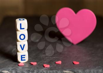Love spelled in wooden blocks with heart shaped cutouts for Valentines day with copy space