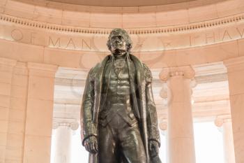 Bronze statue of Thomas Jefferson in Jefferson Memorial in Washington DC as setting sun illuminates interior of the monument