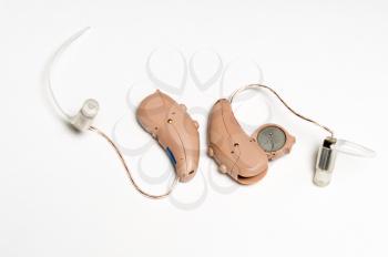 Macro close up of a matched pair of tiny modern hearing aid showing battery on white isolated background