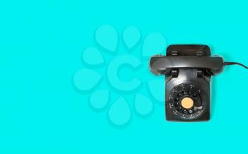 Aerial view of old and antique rotary telephone on turquoise background
