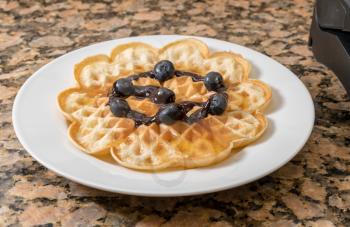 Norwegian heart shaped waffle with blueberries, chocolate sauce and maple syrup