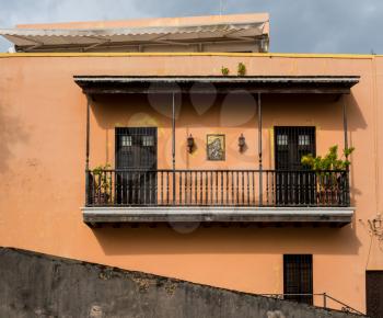 Wooden balcony on orange or ochre colored house in streets of Old San Juan, PR