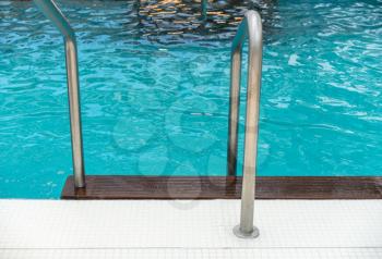 Stainless steel railings and teak steps into luxury swimming pool