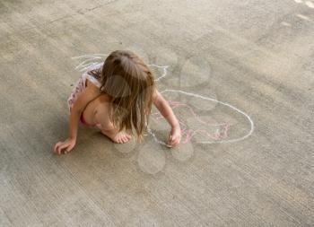 Small preschool girl drawing a chalk circle around the outline of an animal such as a cat or dog on concrete driveway