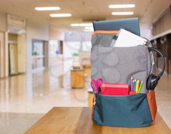 Backpack filled with back to school supplies on a table in a bright entrance hall to college