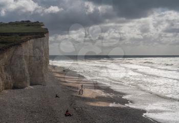 EASTBOURNE, UK - 21 SEPTEMBER 2018: Tourists on the beach on stormy day at Birling Gap near Eastbourne