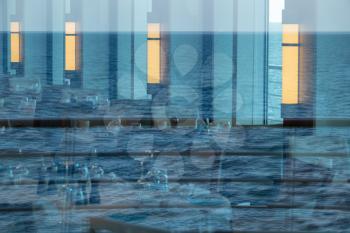 Reflections of ocean in windows around modern restaurant on luxury cruise ship at sea