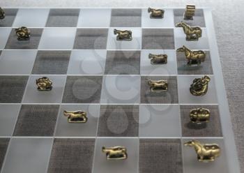 Historic old chinese metal chess pieces on modern glass chessboard