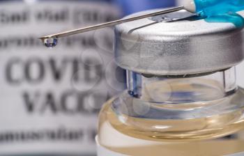 Covid-19 coronavirus vaccine with hypodermic syringe needle with droplet of liquid on tip