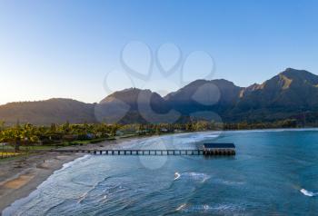 Aerial panoramic image at sunrise off the coast over Hanalei Bay and pier on Hawaiian island of Kauai