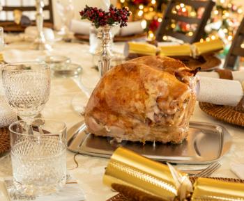 Turkey breast crown ready for carving on traditional British Christmas lunch table setting