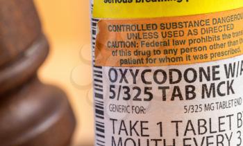 Oxycodone is the generic name for opoid pain killing tablets. Prescription bottle for pills and tablets with judge's gavel for court decision