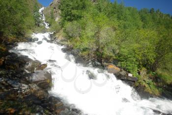 The mountain river in the mountains. Current through the gorge the river. Stones and rocky land near the river. Beautiful mountain landscape.