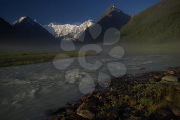 The mountain river in the mountains. Current through the gorge the river. Stones and rocky land near the river. Beautiful mountain landscape.