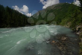 The mountain river in the mountains. Current through the gorge the river. Stones and rocky land near the river. Beautiful mountain landscape.