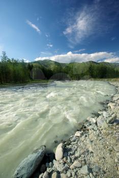 The mountain river in the mountains. Current through the gorge the river. Stones and rocky land near the river. Beautiful mountain landscape.