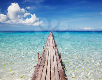 Wooden pier on a tropical island, clear sea and blue sky