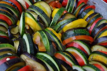 Ratatouille. Vegetable dish. Peasant food. Vegetables, cut into slices. Zucchini, pepper, tomato, eggplant. Kitchen. Recipes. It is useful. Close-up. Horizontal