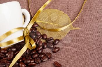 White coffee cup, yellow ribbon and coffee beans 