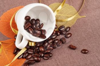White coffee cup, orange autumn leaves and coffee beans 