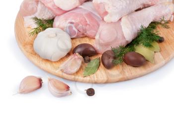 Raw chicken legs with olives and garlic on a wooden board