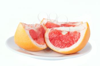 Grapefruit juicy slices on plate isolated on a white background