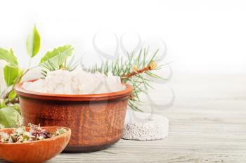 Aromatic bath salt and dried herbs on a wooden surface