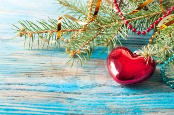 Red Christmas decoration and fir branch on a blue wooden background