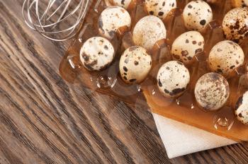 Quail eggs in a plastic container on a wooden background